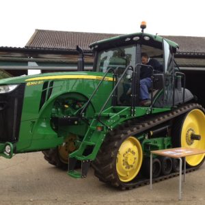 A John Deere green and yellow tractor with caterpillar tracks, not wheels
