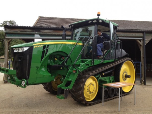 A John Deere green and yellow tractor with caterpillar tracks, not wheels