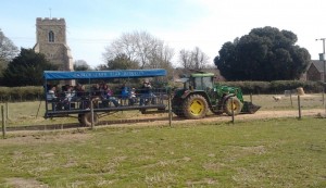 A tractor pulling a trailer full of visitors with the church in the background
